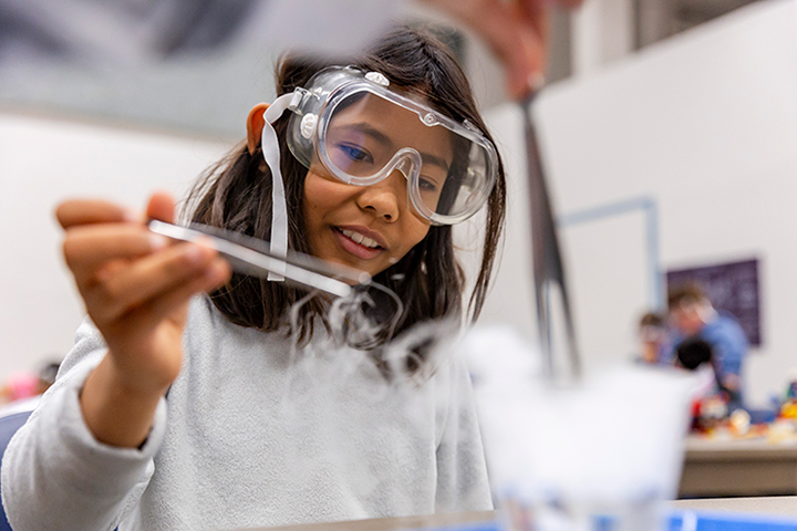 A girl wearing safety goggles conducting an experiment with dry ice
